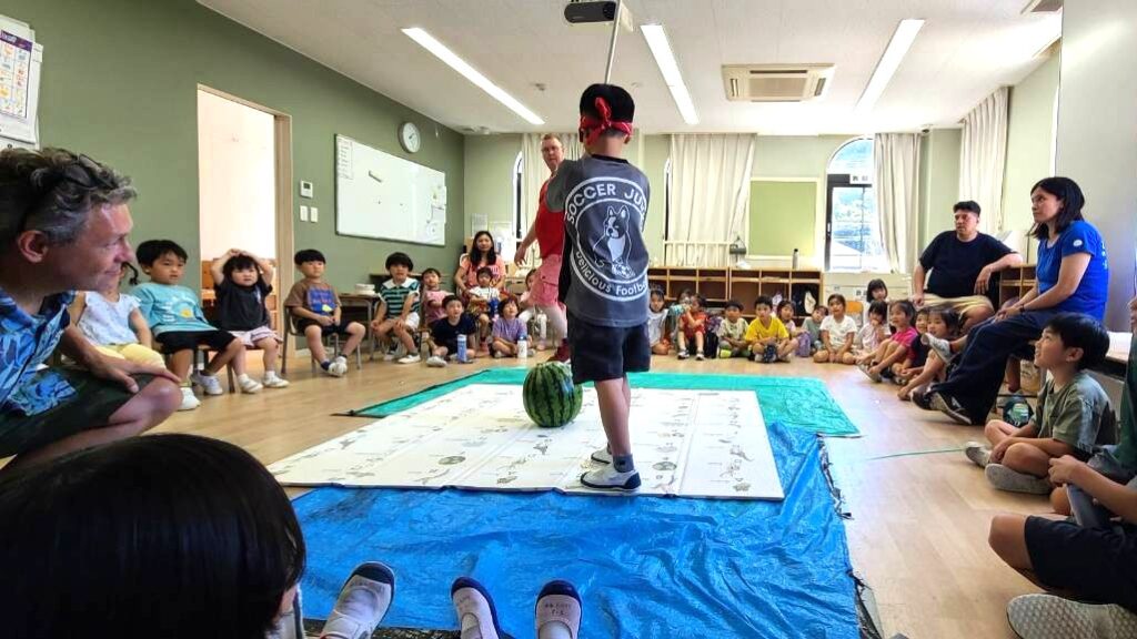 サマースクールのアクティビティで外国人講師特製ポップコーンとスイカ割りを楽しむ子どもたち